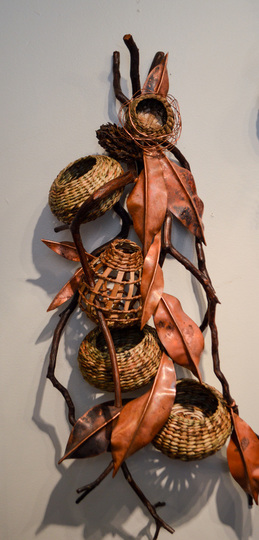 Handmade copper ornaments adorn a rustic contemporary basket sculpture made by Matt Tommey in the River Arts District of Asheville, North Carolina.